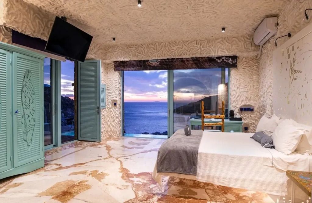 Modernes Schlafzimmer mit großem Fenster und Meerblick in der Sea of Smiles Suite