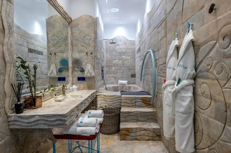 Luxuriöses Badezimmer mit Steinelementen und Bademänteln