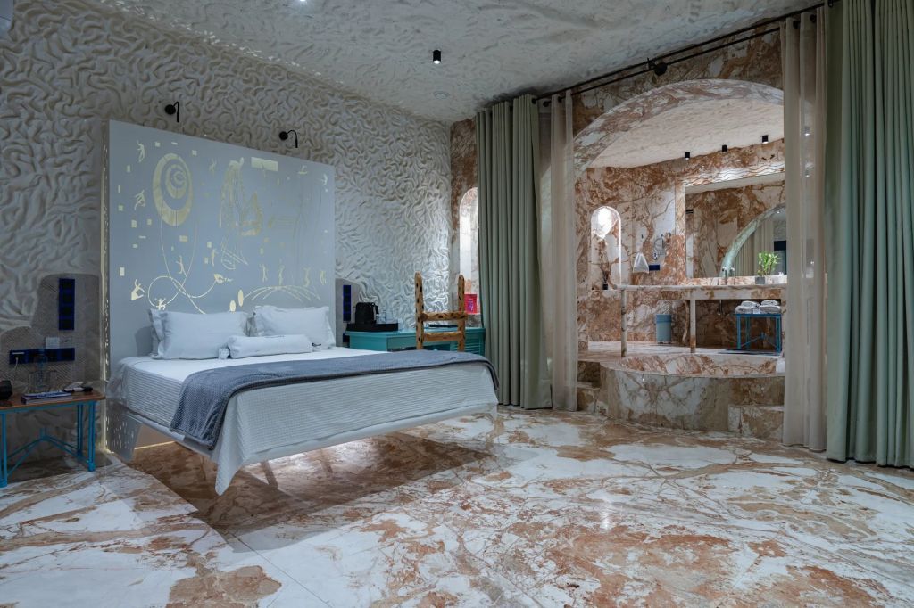 Geräumiges Zimmer mit Marmoroptik und stilvollem Bett in moderner Umgebung.