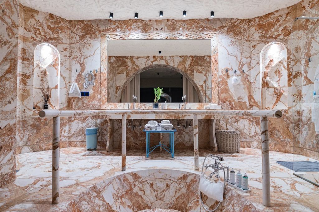Großes Badezimmer mit eleganten Marmorwänden und Doppelwaschbecken.