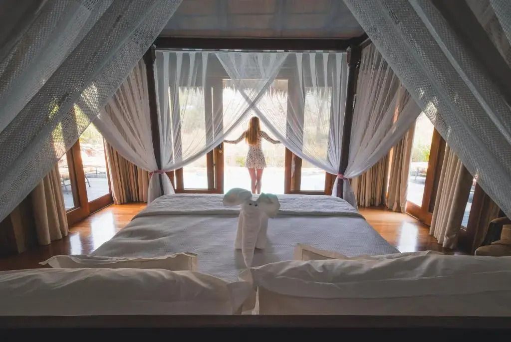 Person steht vor einem Himmelbett mit Baldachin und genießt den Ausblick
