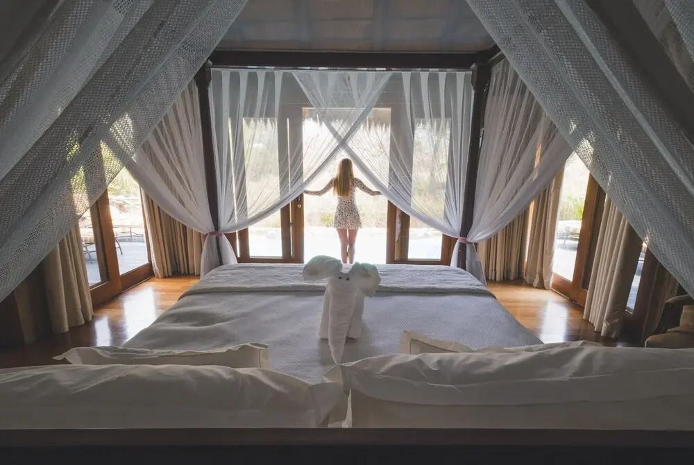 Elegantes Schlafzimmer mit großen Fenstern und Baldachinvorhang