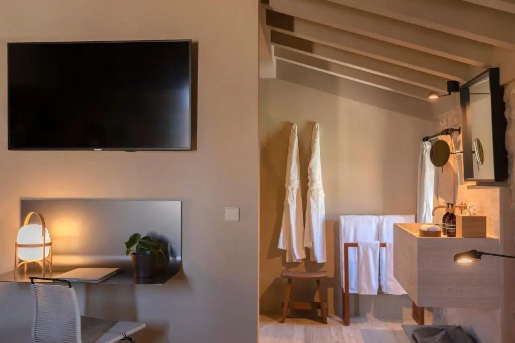 Modernes Hotelzimmer mit stilvollem Interieur und Wand-TV, helle Farben und Holzelemente