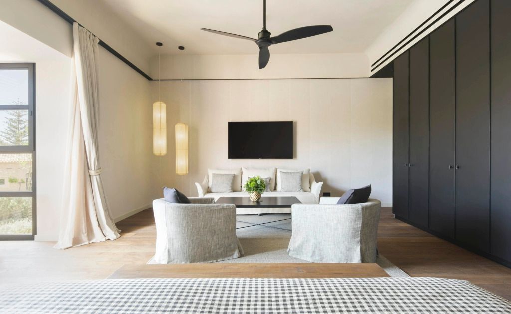 Elegantes Wohnzimmer in einer Suite mit Sofa, Sessel, Fernseher und Hängelampen.