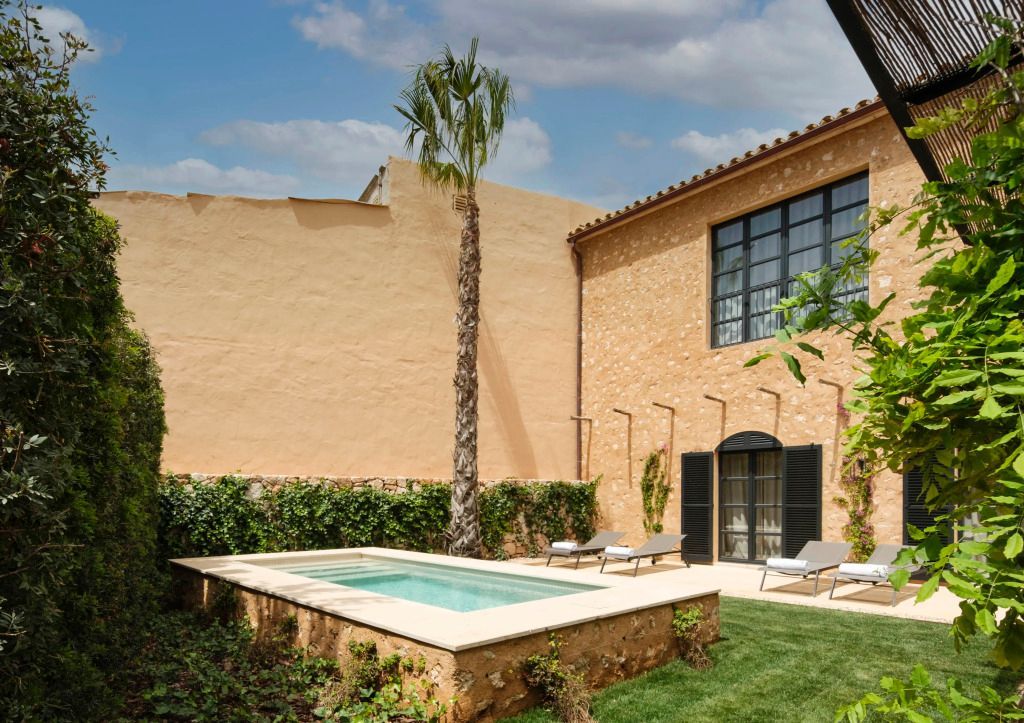 Charmanter Innenhof mit kleinem privatem Pool und Liegestühlen, umgeben von einer Steinmauer.