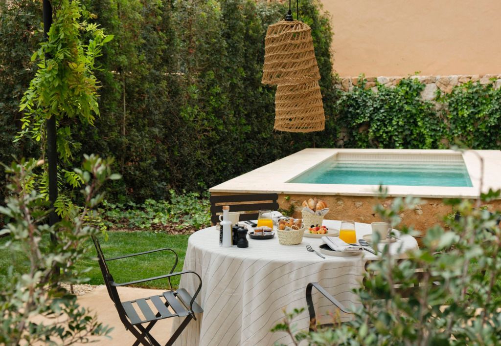 Gemütliche Gartenecke mit Tisch und Stühlen für ein entspanntes Frühstück am Pool.