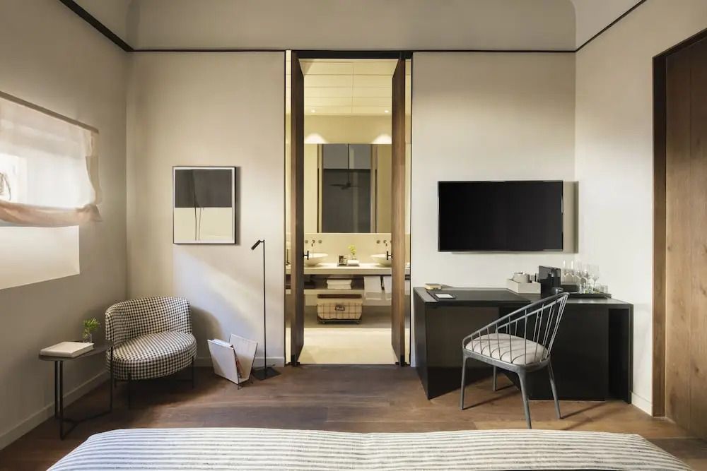 Hotelzimmer mit Schreibtisch, Stuhl, Flachbild-TV und offenem Durchgang zum Bad