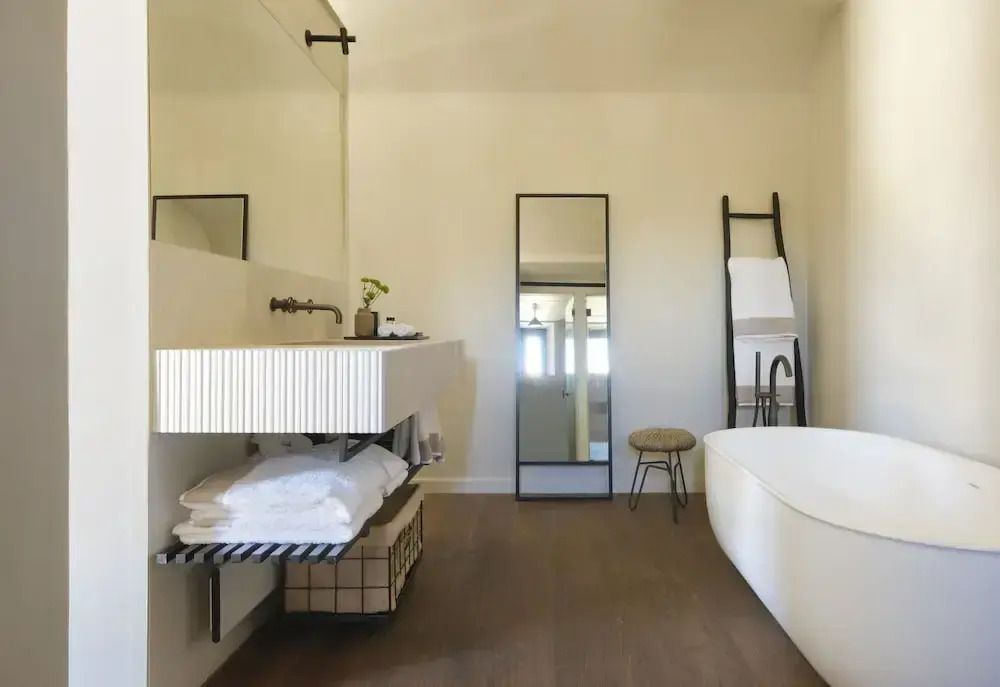 Elegantes Badezimmer mit freistehender Badewanne, großem Spiegel und modernen Akzenten.