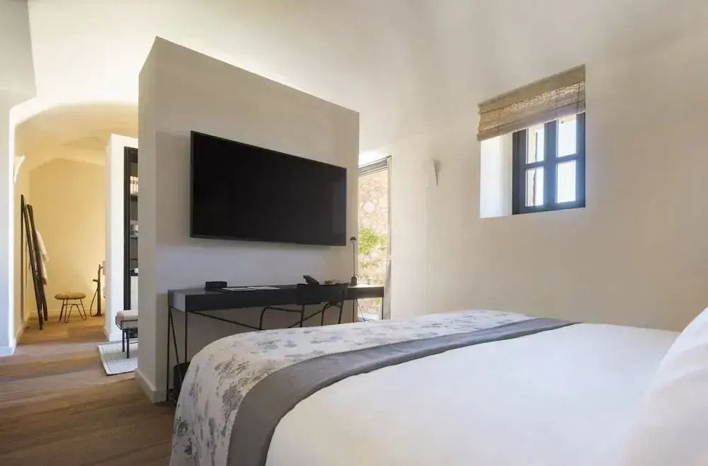 Gemütliches Bett mit Fernseher an der Wand und moderne Einrichtung im Hotelzimmer.