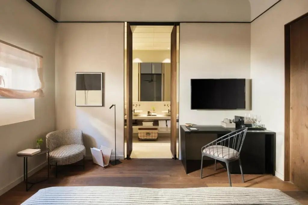Hotelzimmer mit Blick auf TV, Schreibtisch und Tür zum modernen Bad