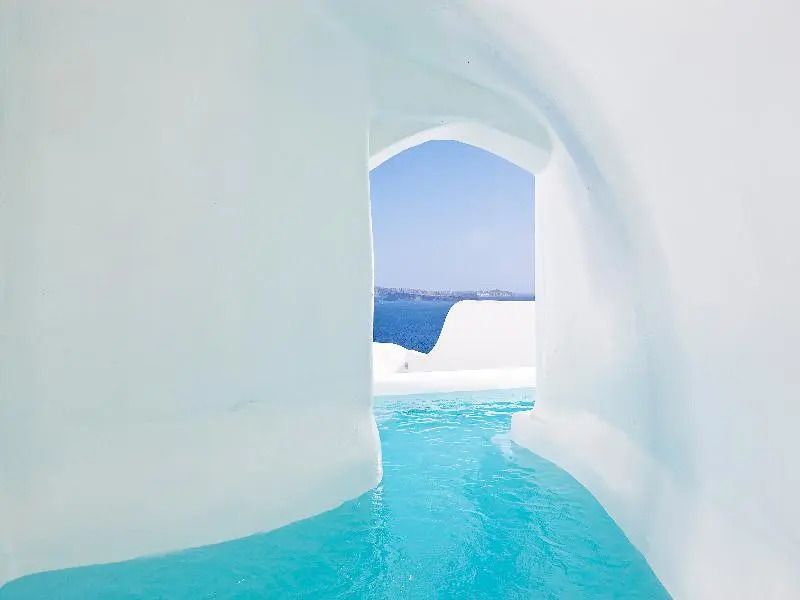 Infinity Pool mit Blick auf das tiefblaue Meer, umgeben von weißen Wänden