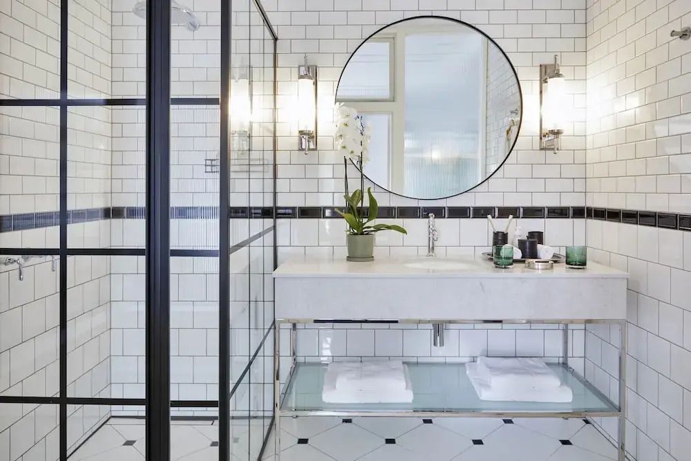 Badezimmer mit großer runder Wandspiegel und moderner Dusche