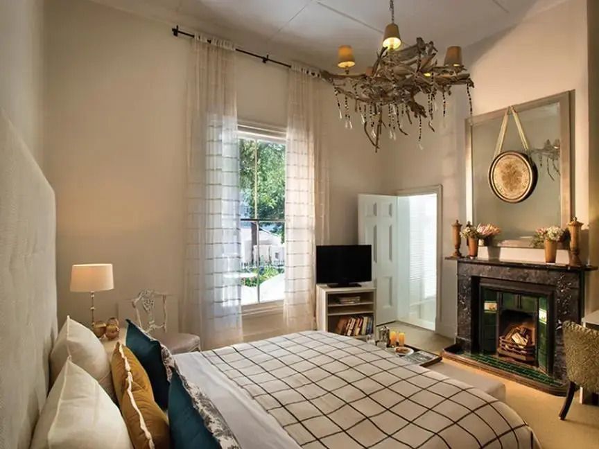 Luxus Schlafzimmer mit elegantem Kronleuchter und gemütlichem Kamin im Cape Cadogan.