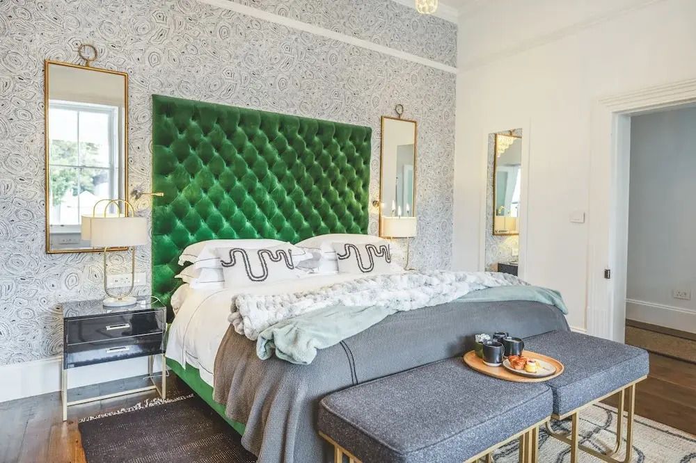 Geräumiges Doppelbett mit grünem, gepolstertem Kopfteil und stilvoller Einrichtung