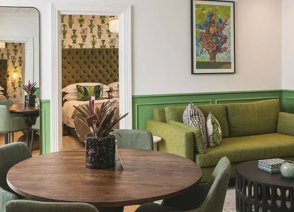 Geräumiges Wohnzimmer mit grünem Sofa und Holztisch in der Suite