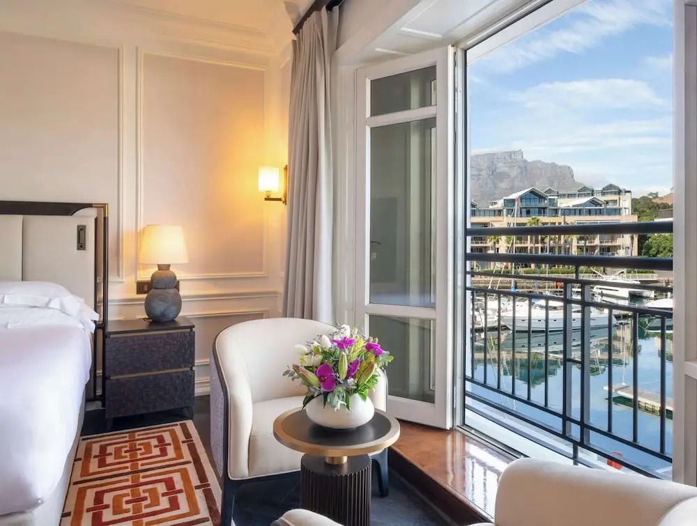 Helles Zimmer mit Doppelbett, Sesseln und Blick auf Tafelberg und Hafen