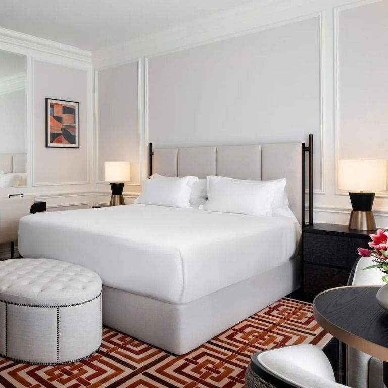 Helles Schlafzimmer einer Suite mit großem Doppelbett und stilvollem Teppich.