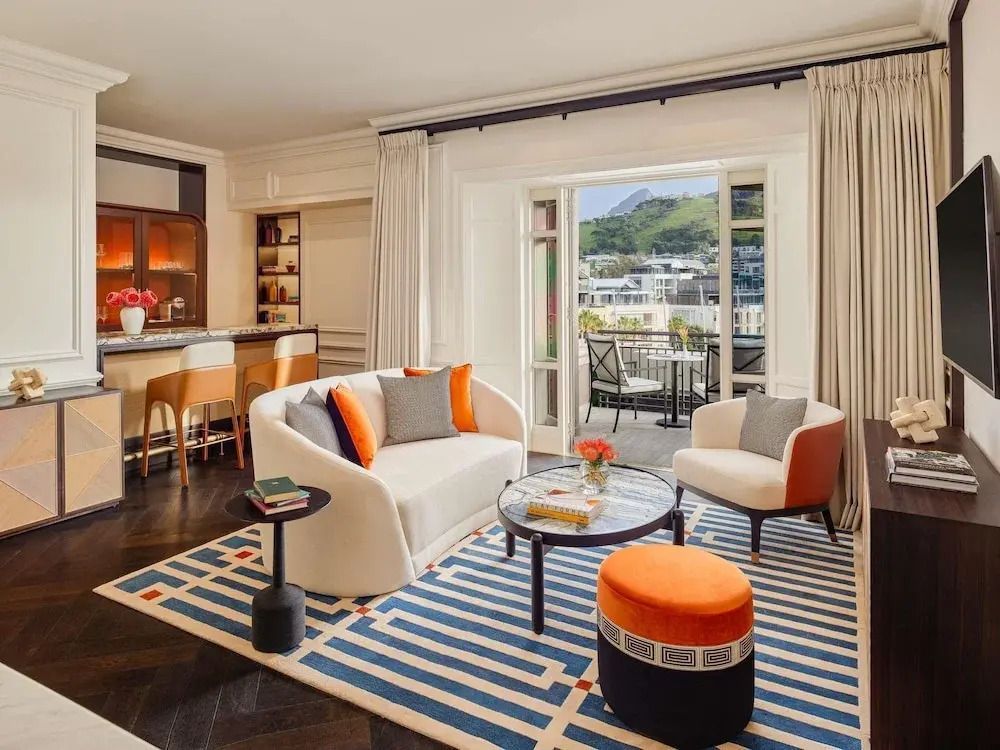 Wohnbereich einer Suite mit moderner Einrichtung und Zugang zum Balkon.