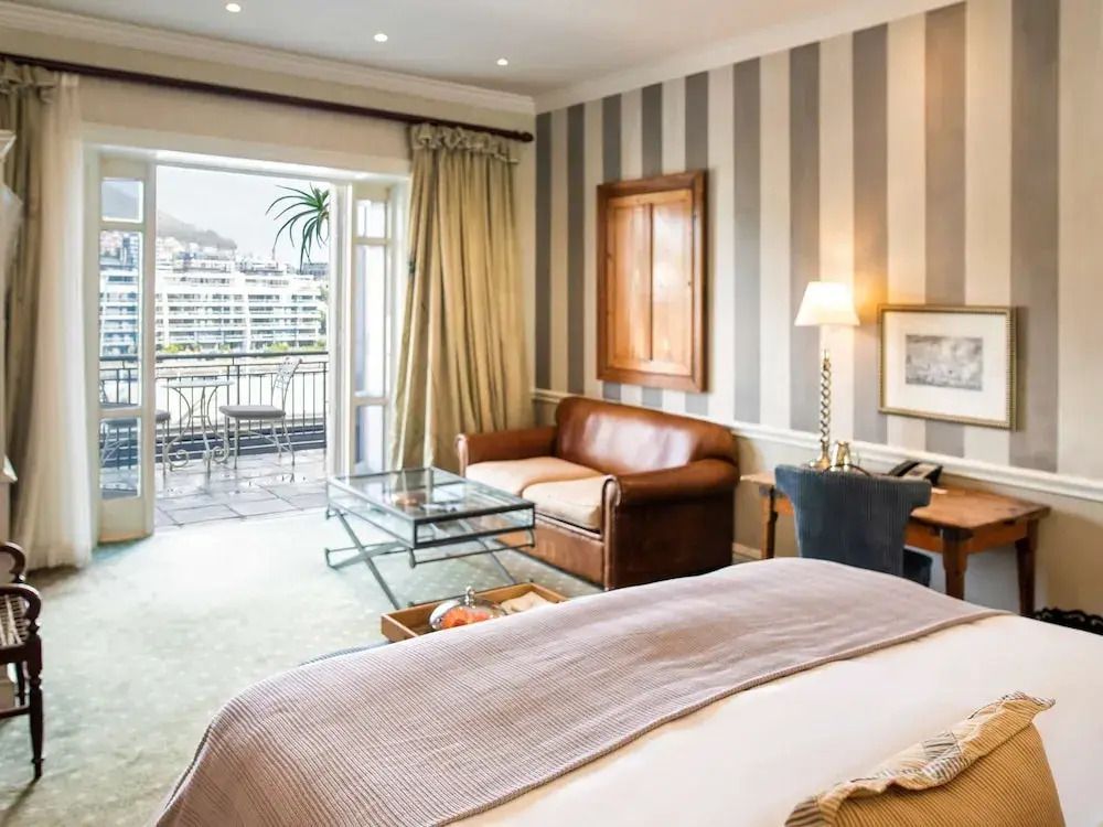 Elegantes Zimmer mit Doppelbett und Zugang zu einem Balkon