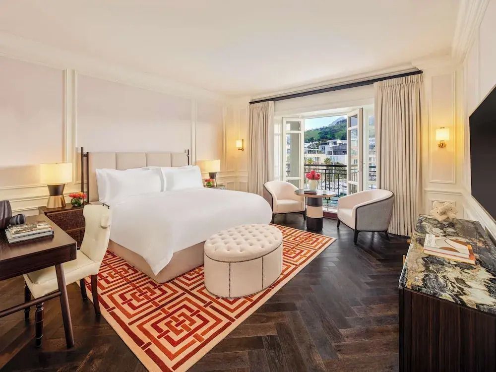 Helles, elegant eingerichtetes Hotelzimmer mit Doppelbett und Balkonblick.
