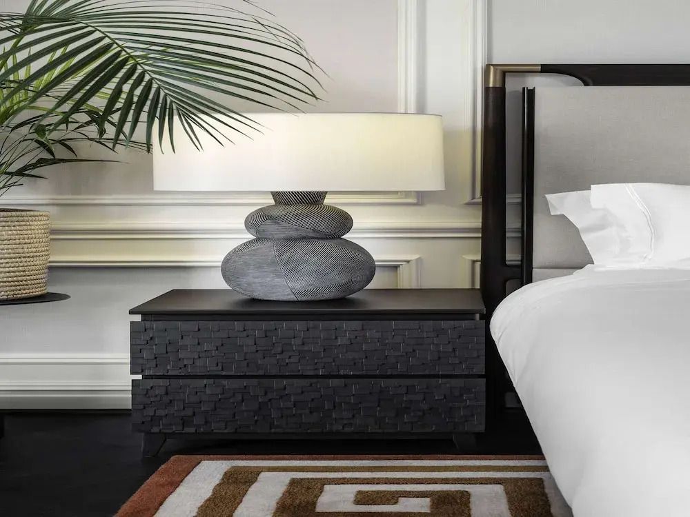 Nachttisch mit Designerlampe neben elegantem Bett.