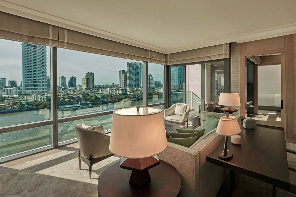 Wohnbereich der Suite mit großen Fenstern und Flussblick in Bangkok