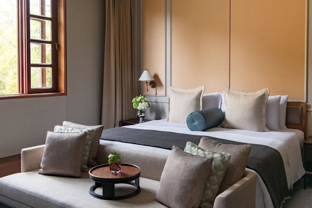 Helles Schlafzimmer mit großem Bett und Sitzbereich in eleganten Farben