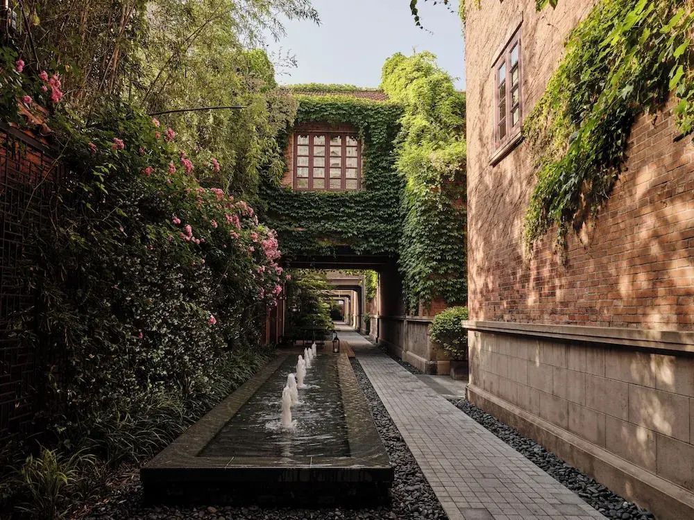 Romantischer Gartenweg mit Kletterpflanzen und Wasserbrunnen.