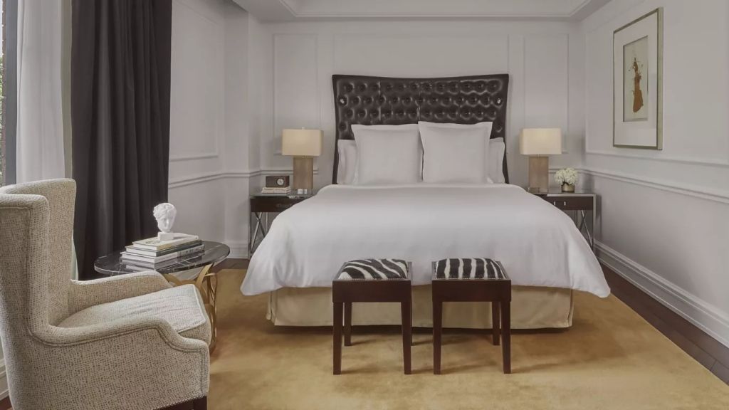 Luxuriöses Schlafzimmer mit eleganten Möbeln und zwei Hockern vor einem großen Bett