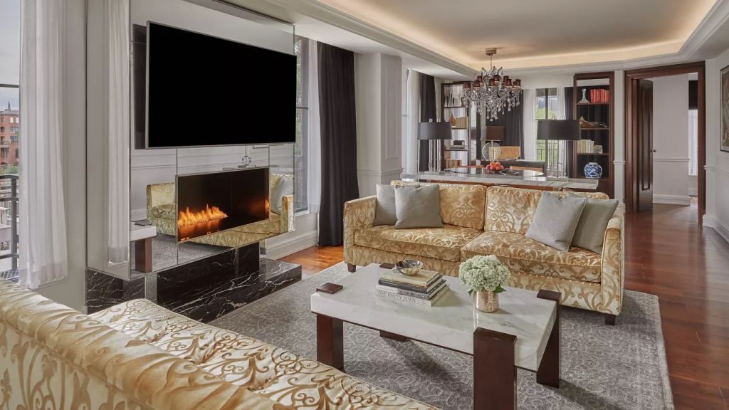 Wohnbereich mit Kamin und goldenen Sofas in der Royal Suite des Hotels