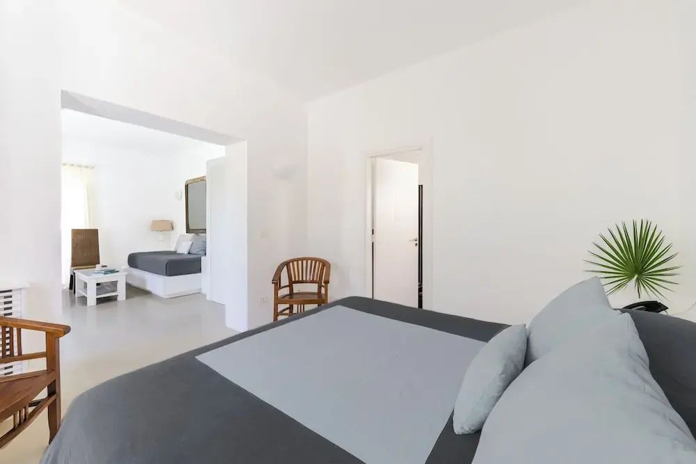 Helle Junior-Suite mit modernen grauen und weißen Akzenten und einem gemütlichen Stuhl