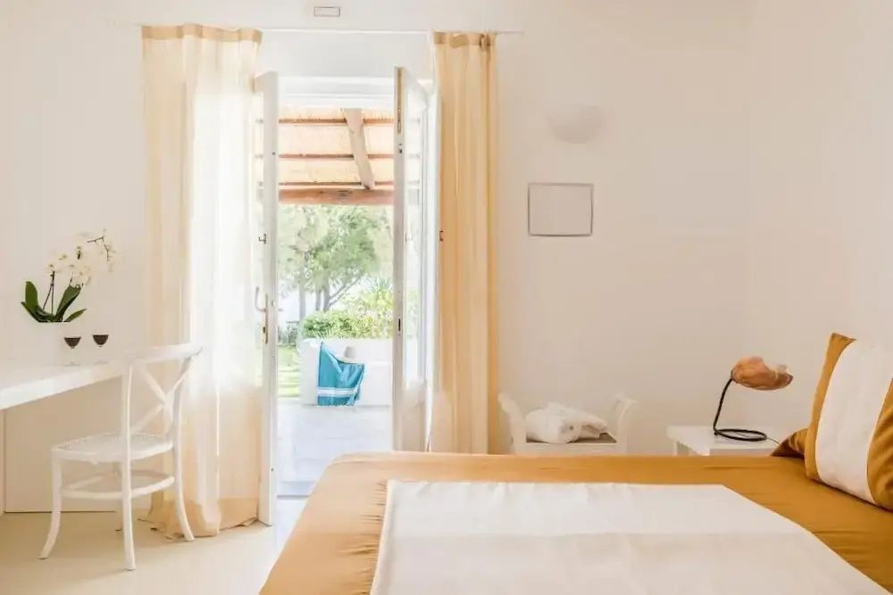 Sonnenlicht dringt durch helle Vorhänge in ein elegantes Doppelzimmer mit Blick auf den Garten.