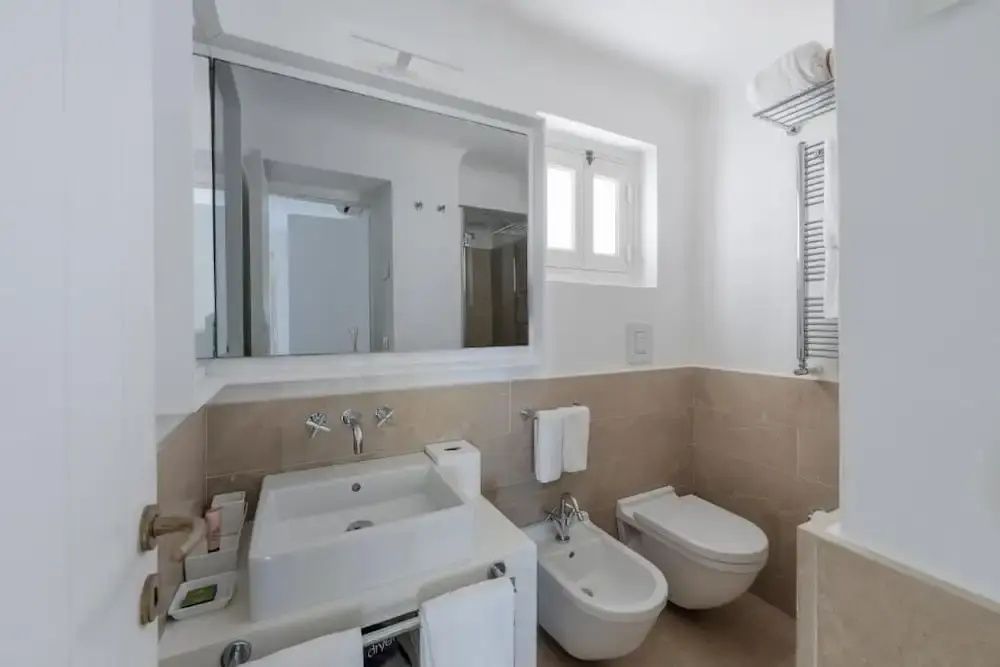 Stilvolles Badezimmer mit großen Spiegeln und modernen Armaturen vor neutralen Tönen.