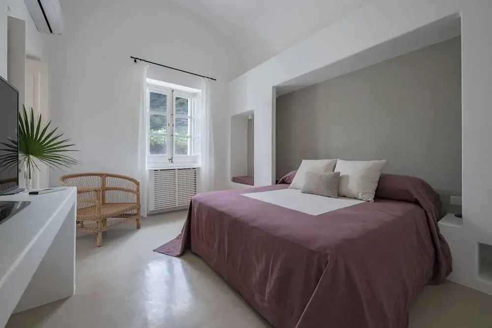 Helles Doppelzimmer mit Doppelbett, Fenster und Korbstuhl