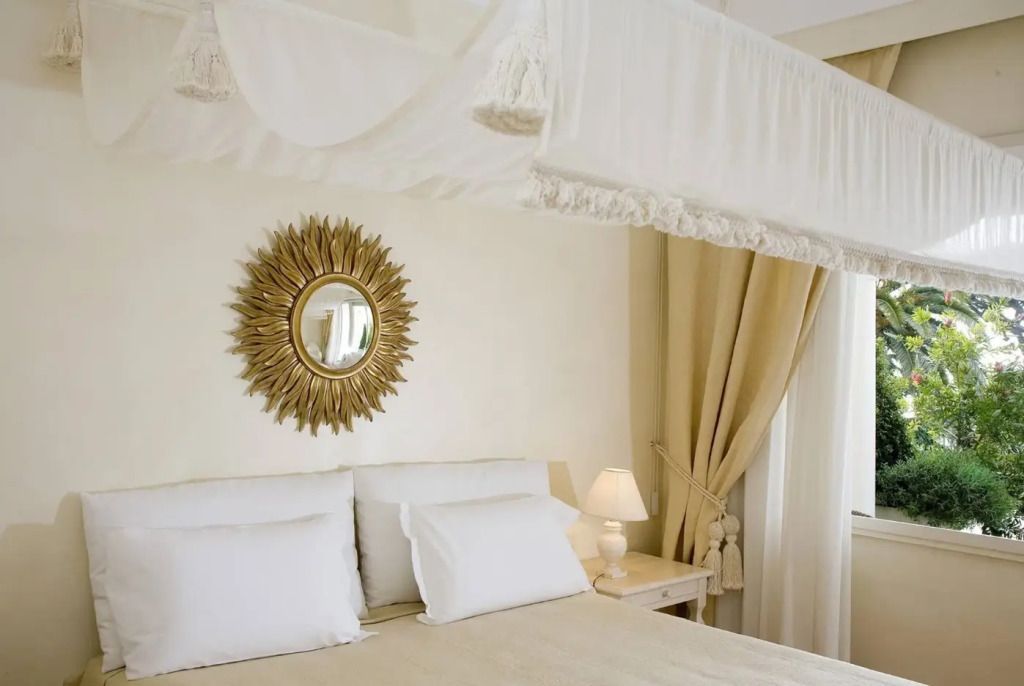 Elegantes Doppelzimmer mit goldener Spiegeldeko und weißen Vorhängen