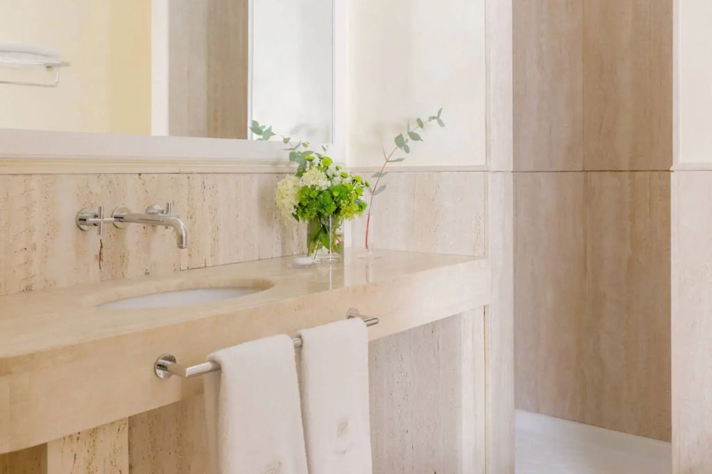 Helles Badezimmer mit weißem Waschbecken und frischen Blumen