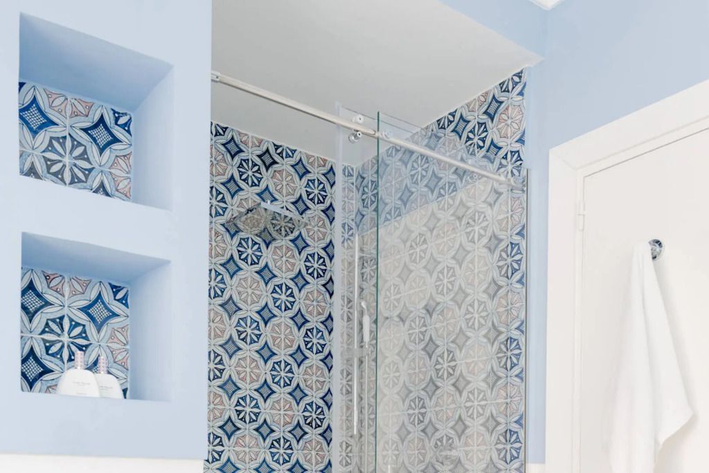 Modernes Badezimmer mit blau-weißen Fliesen und Glasdusche