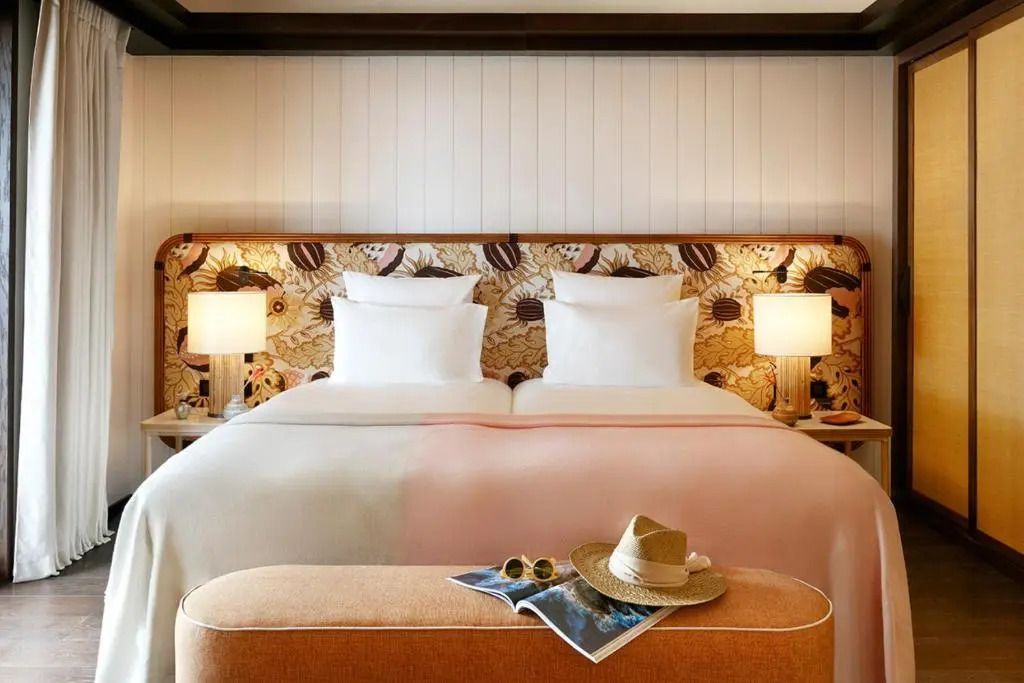 Elegantes Schlafzimmer mit Doppelbett in der Deluxe Suite mit floralem Kopfteil.