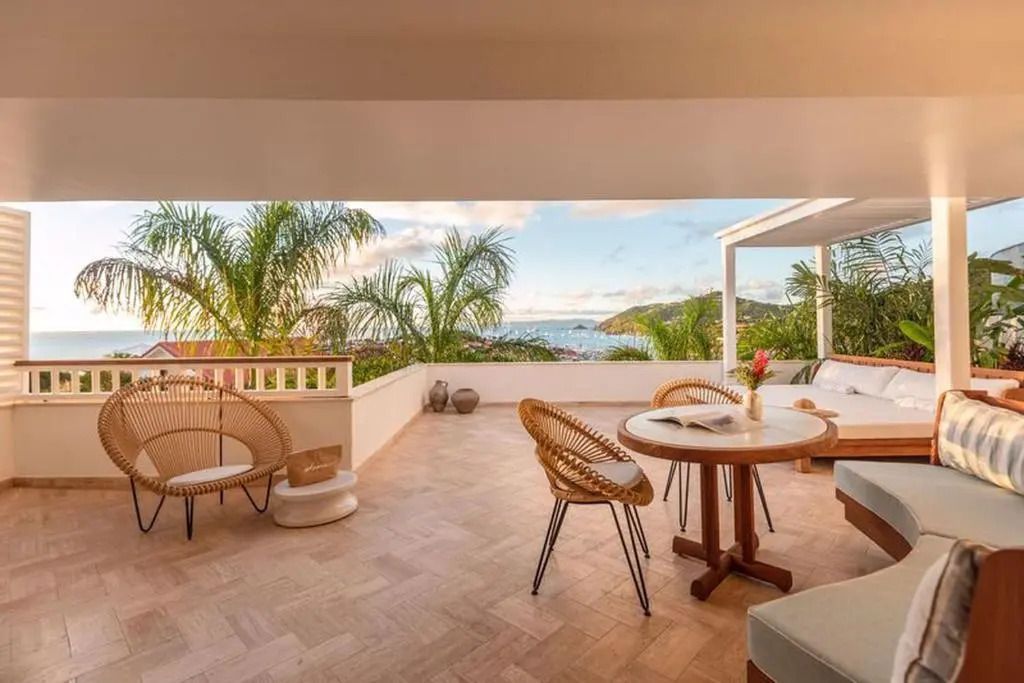 Große Terrasse mit Esstisch und Blick auf das Meer und tropische Pflanzen