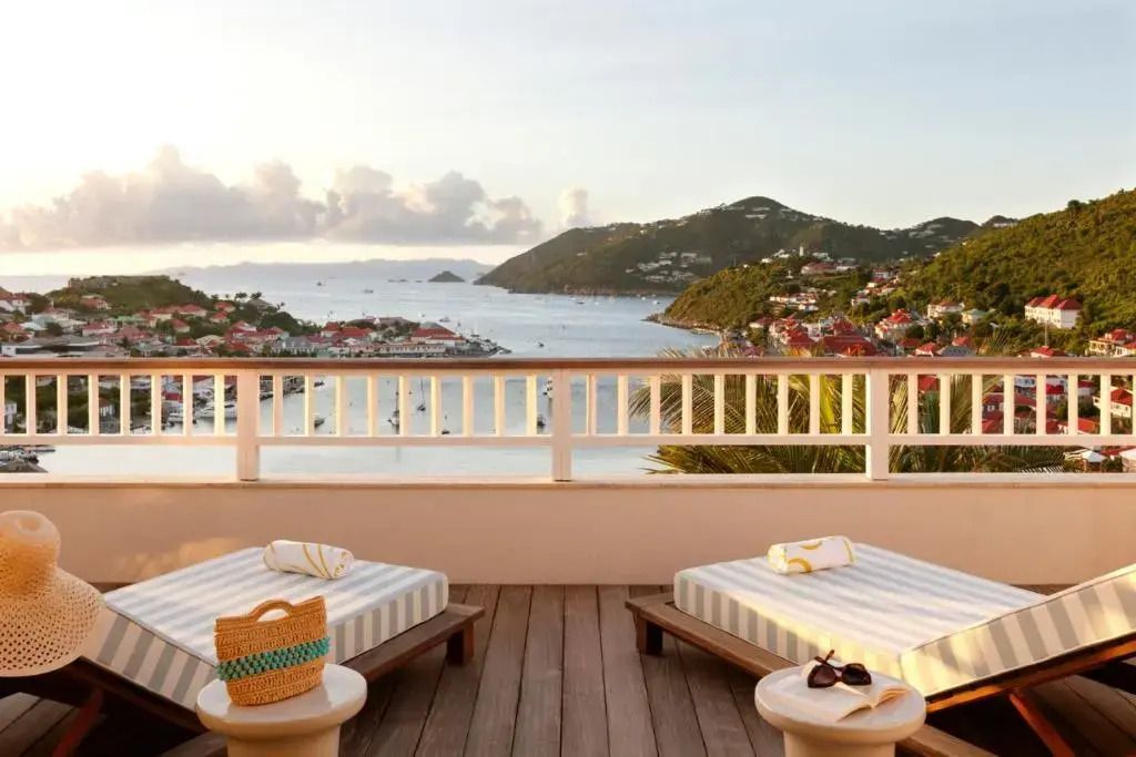 Terrasse mit Liegestühlen und Blick auf die Bucht im Sonnenuntergang