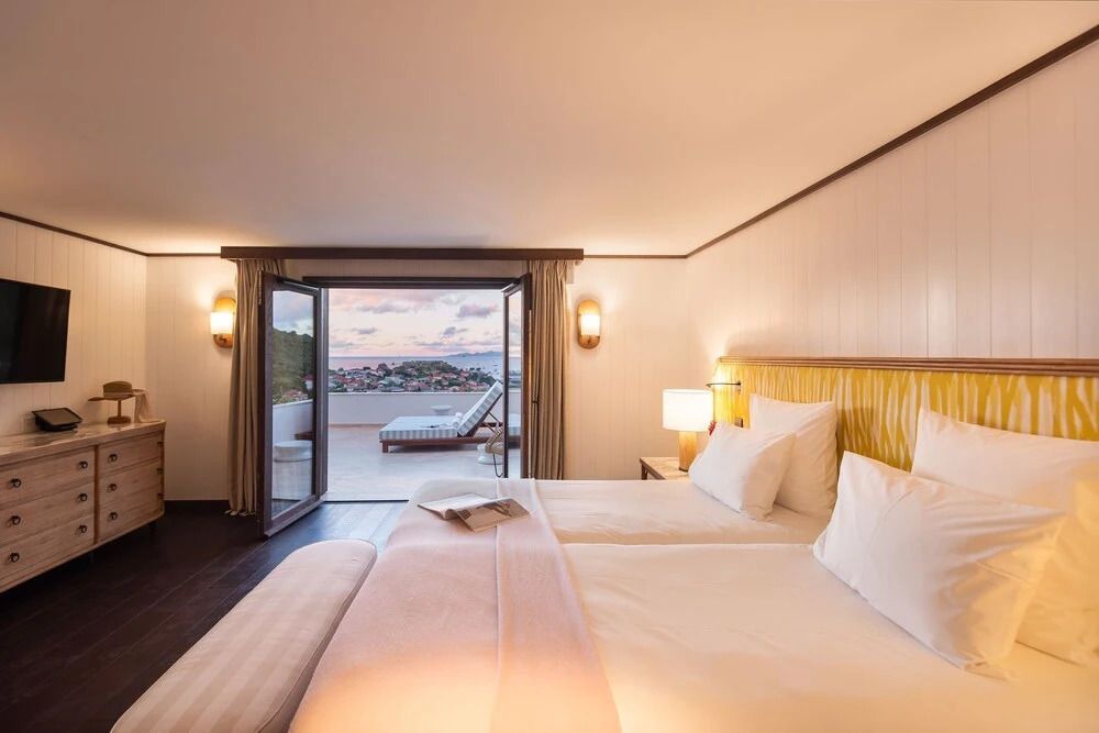Geräumiges Schlafzimmer mit Doppelbett und Zugang zum Balkon mit Meerblick.