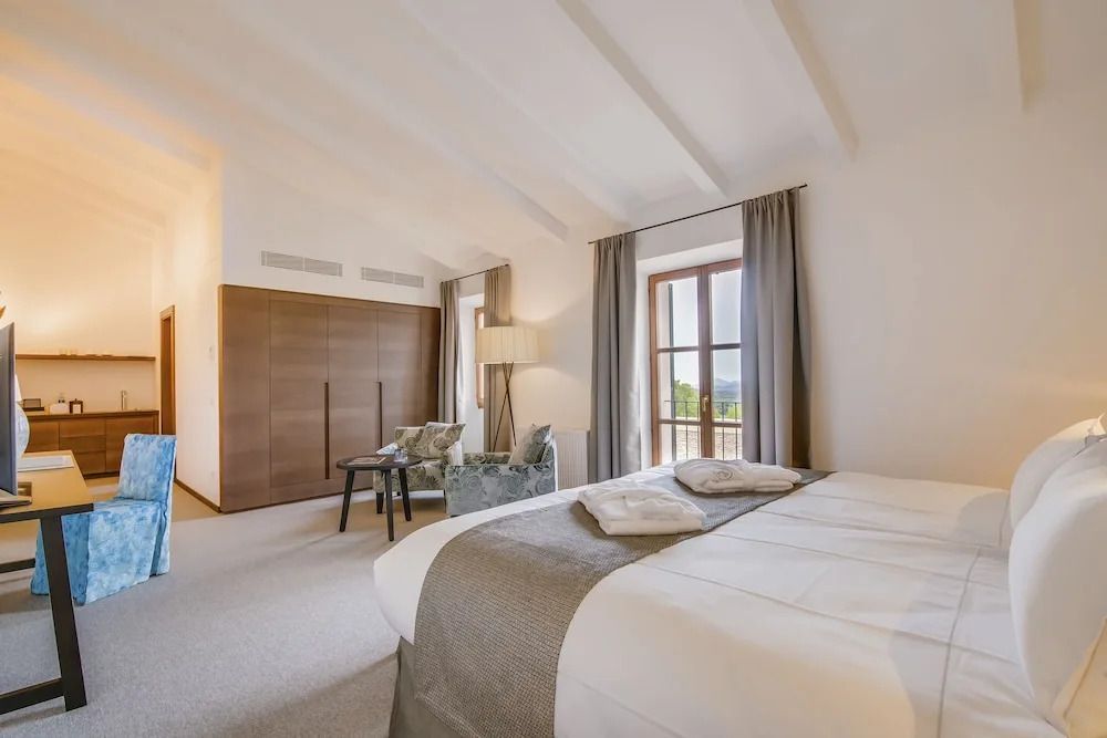 Deluxe Zimmeransicht mit Bett, Schrank und großem Fenster