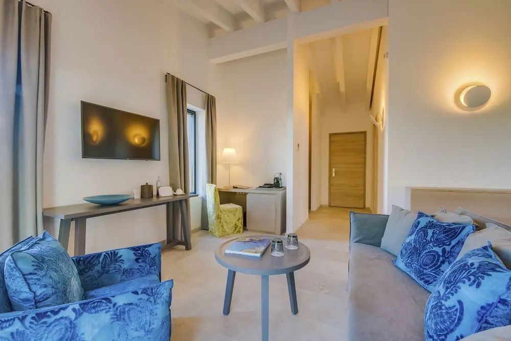 Helles Wohnbereich der Suite mit Sofa, Fernseher und Schreibtisch