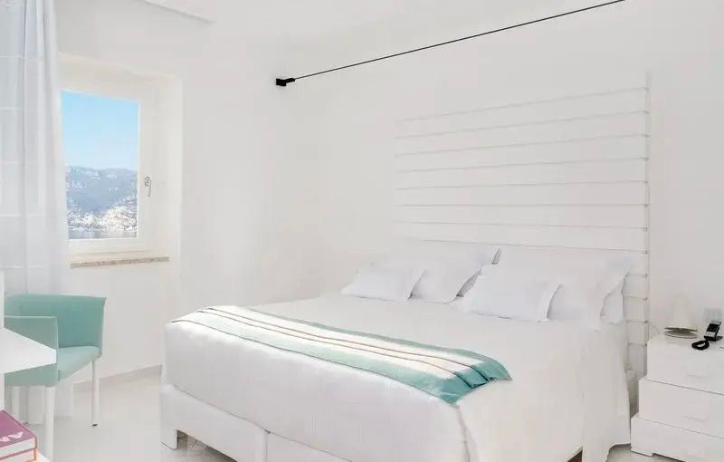 Modernes Hotelzimmer mit großem Doppelbett und elegantem weißen Design