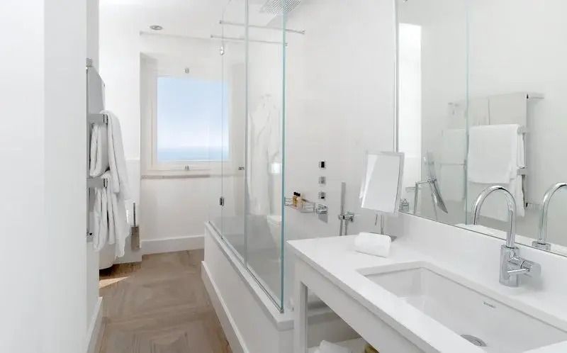 Modernes Badezimmer mit Glasdusche und Fenster mit Meerblick