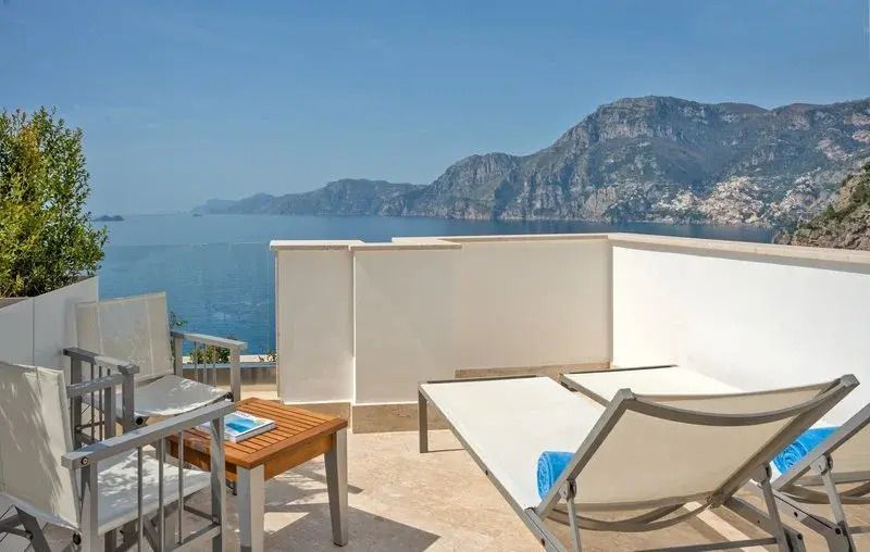 Terrasse mit Liegestühlen und atemberaubendem Blick auf das Meer und Berge.