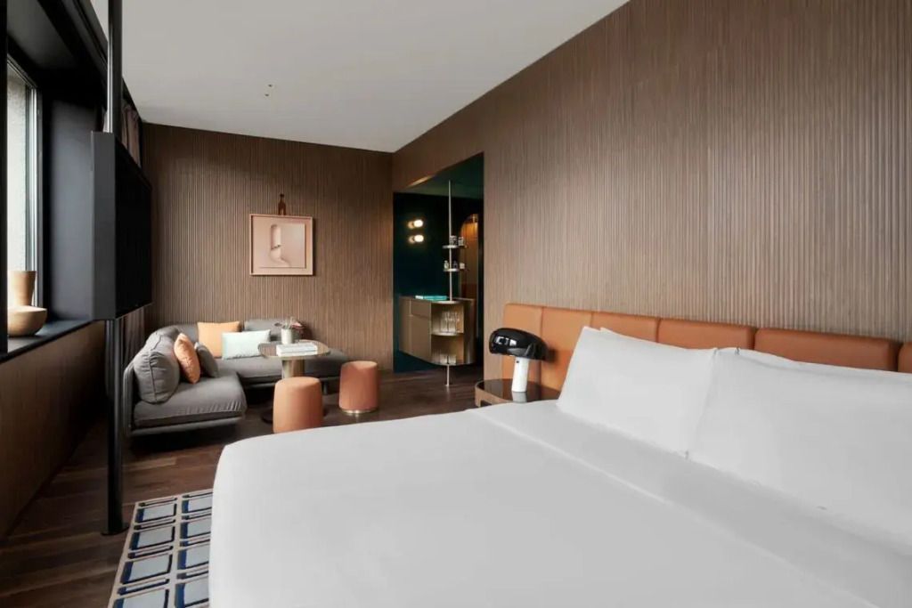 Modernes Hotelzimmer mit Doppelbett und eleganter Sitzecke in warmen Tönen