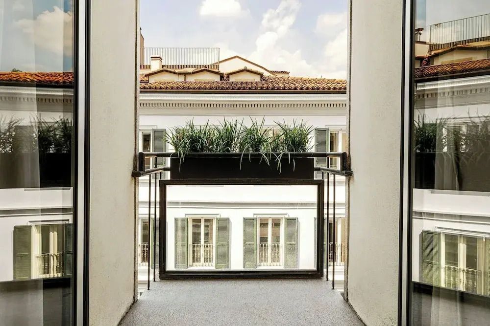 Blick vom Balkon auf ein gegenüberliegendes Gebäude mit Pflanzen im Vordergrund