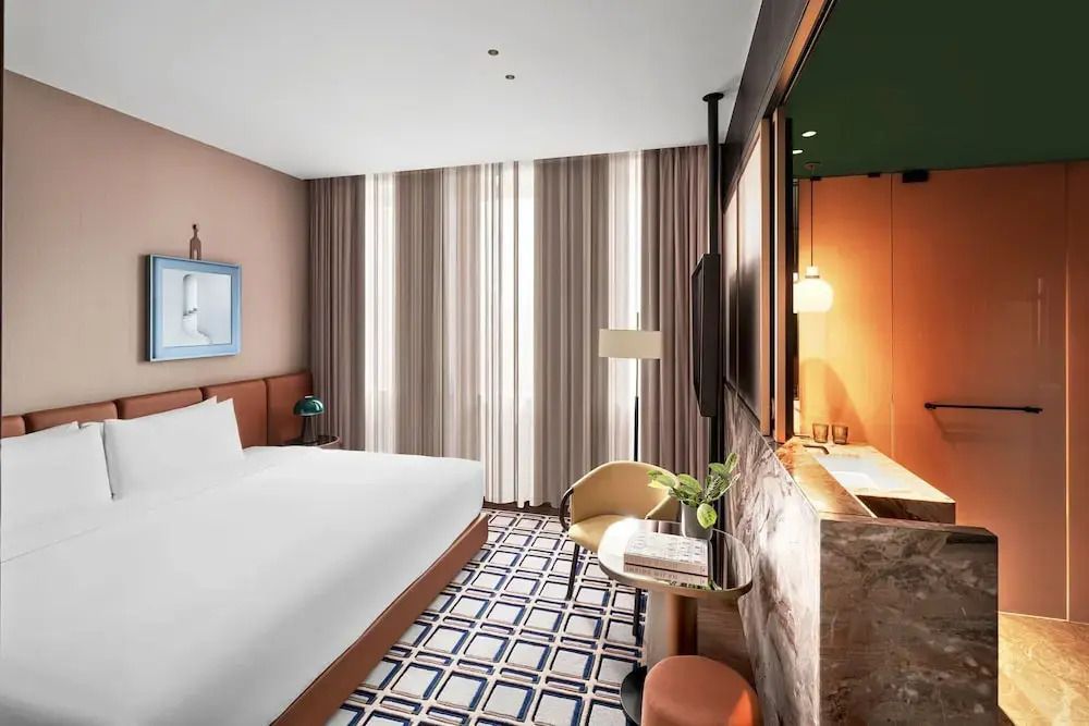 Helles Hotelzimmer mit Doppelbett und bodenlangen Vorhängen