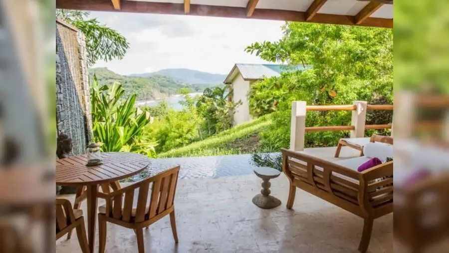 Terrasse mit Blick auf grüne Hügel und den Infinity Pool